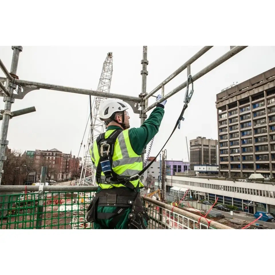 Man wearing hi-vis jacket, harness and helmet attached to a scaffolding structure