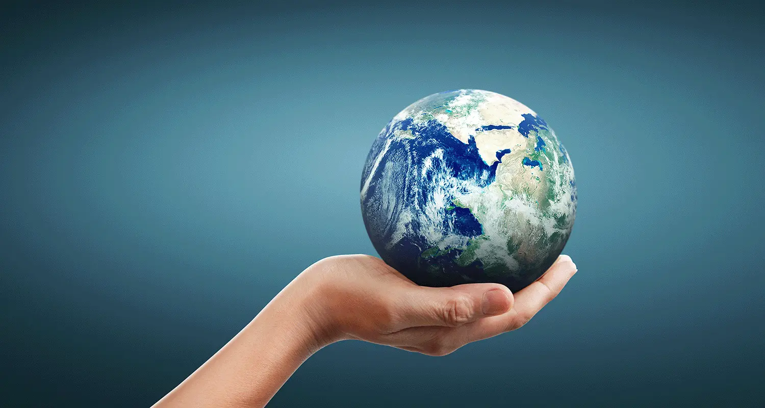 Hand holding a small globe on a blue background