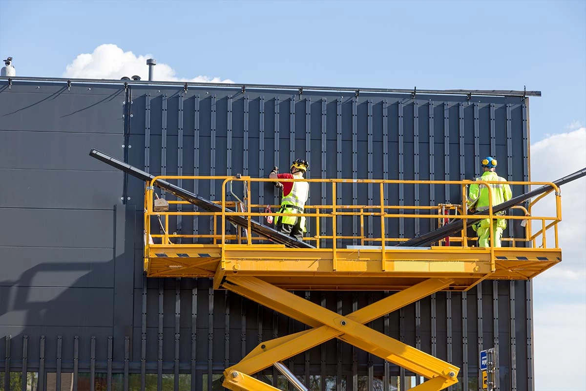 Two delegates in hi-vis PPE on a yellow elevated work platform on a HSS Training Work at Height course